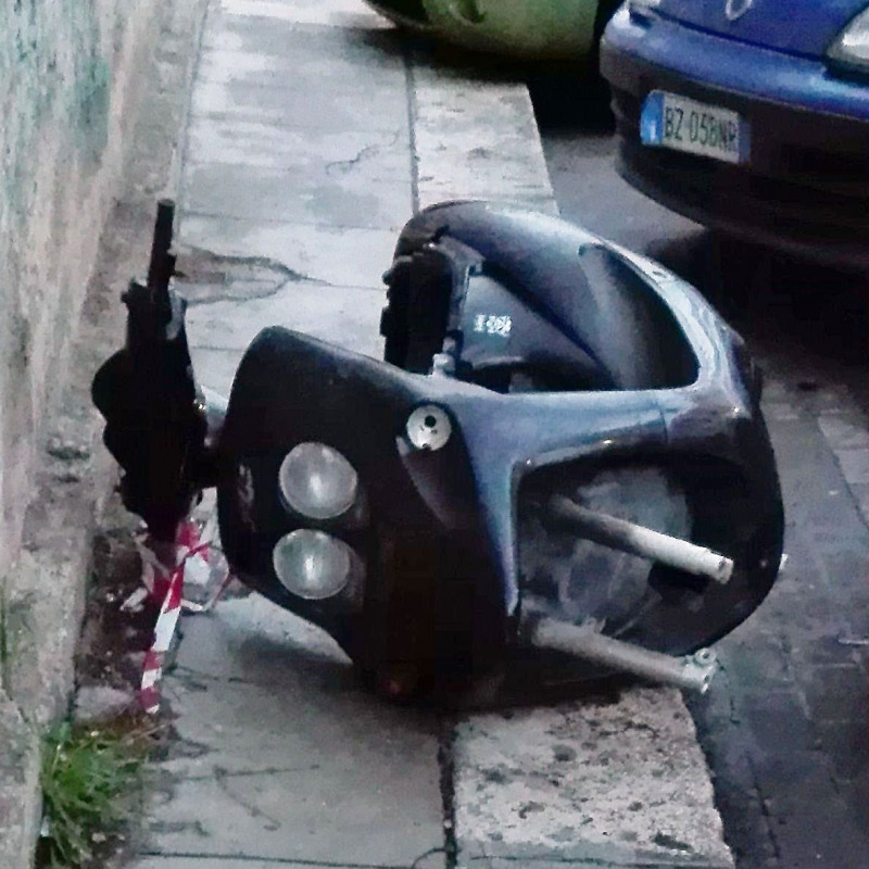 La carcassa di un scooter abbandonata su un marciapiedi di via Serradifalco nella foto di Santo Mannala