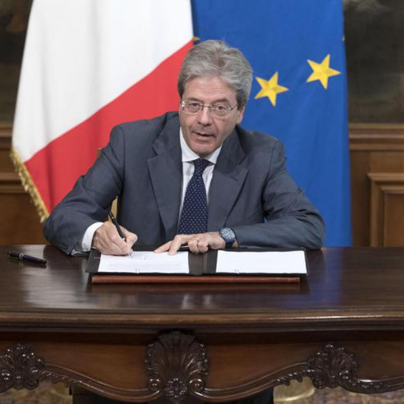 Il premier Paolo Gentiloni firma il testo dell'Ape volontaria - Ansa