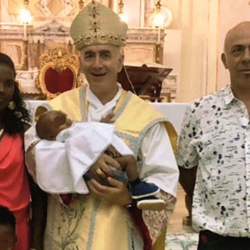 Monsignor Antonio Staglianò, vescovo di Noto, con in braccio il bimbo eritreo battezzato