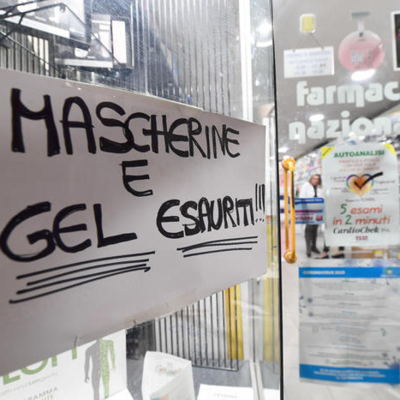 Un cartello esposto sulla vetrina esterna di una Farmacia genovese, che segnala l'esaurimento di gel disifettanti e mascherine di protezione per il viso (archivio)