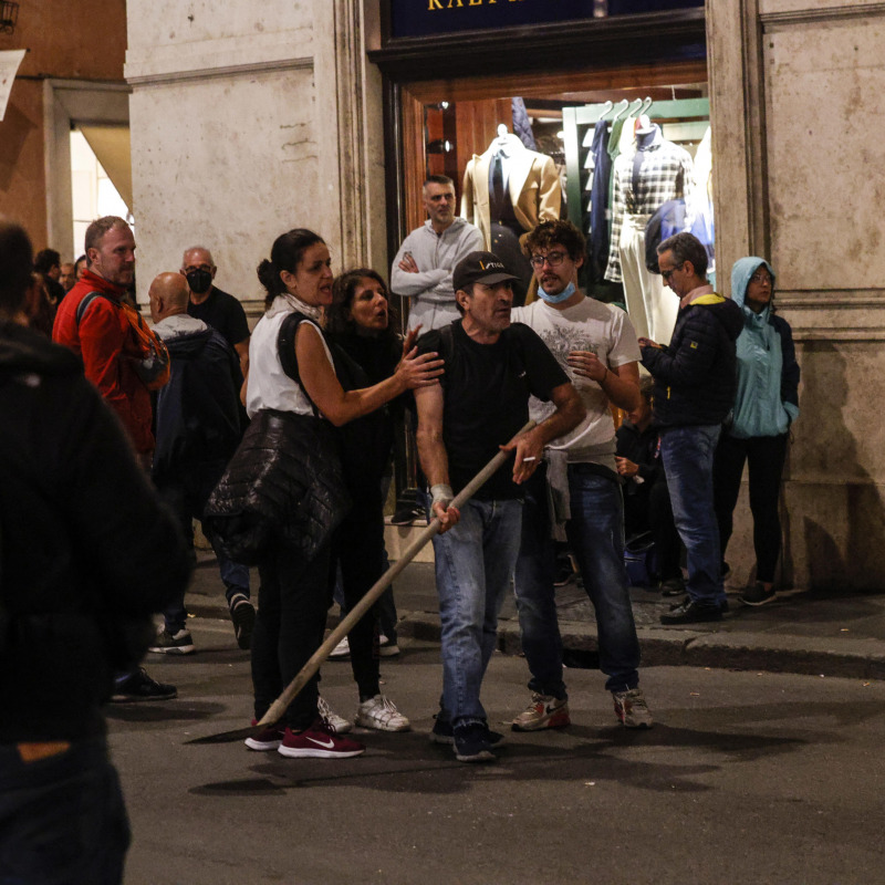 Un uomo lancia una pala in direzione delle forze dell'ordine durante gli scontri nel centro di Roma