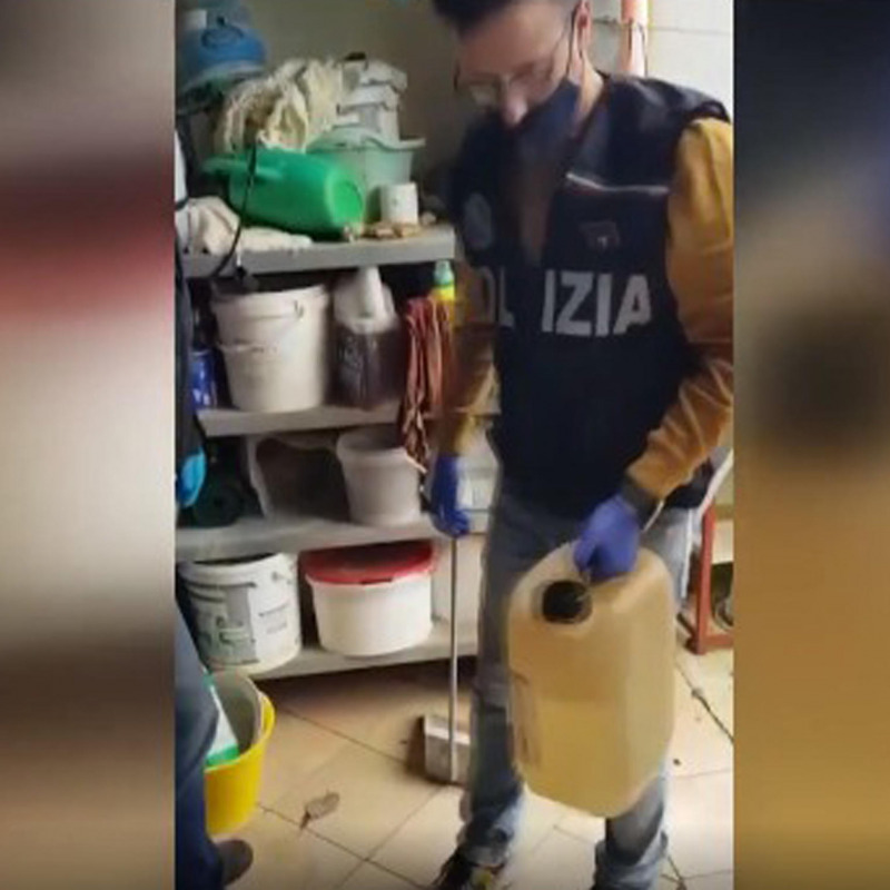 La polizia con una tanica di acido trovata in casa del commerciante di Torretta: è un fermo immagine da un video diffuso dalla Digos di Torino