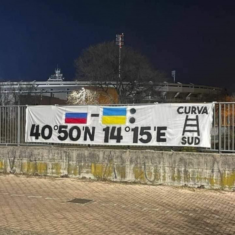 Uno striscione con le coordinate geografiche di Napoli allo stadio di Verona,