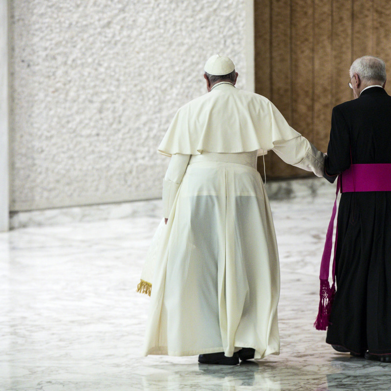 Il Papa si appoggia ad un alto prelato per camminare
