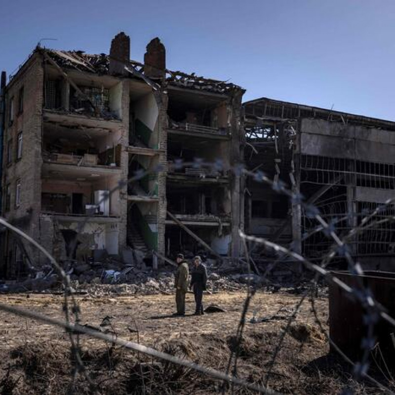 People stand beside damaged buildings at the Vizar company military-industrial complex, after the site was hit by overnight Russian strikes, in the town of Vyshneve, southwestern suburbs of Kyiv, on April 15, 2022. - A Ukrainian military factory outside Kyiv that produced missiles allegedly used to hit Russia's Moskva warship was partly destroyed by overnight Russian strikes, an AFP journalist at the scene saw on April 15. A workshop and an administrative building at the Vizar plant were seriously damaged. (Photo by FADEL SENNA / AFP)