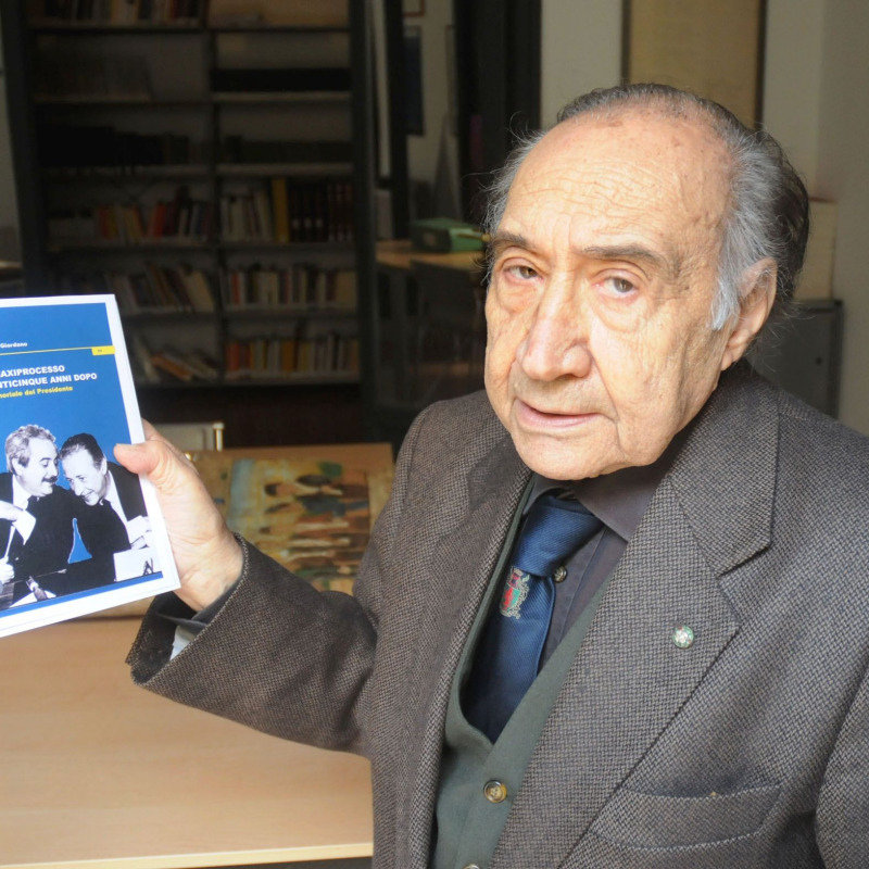 Alfonso Giordano mostra il libro sul maxiprocesso con la foto di Falcone e Borsellino in copertina