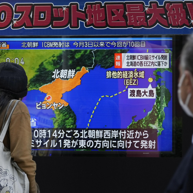 Alcuni giapponesi leggono la notizia del missile su una tv in strada