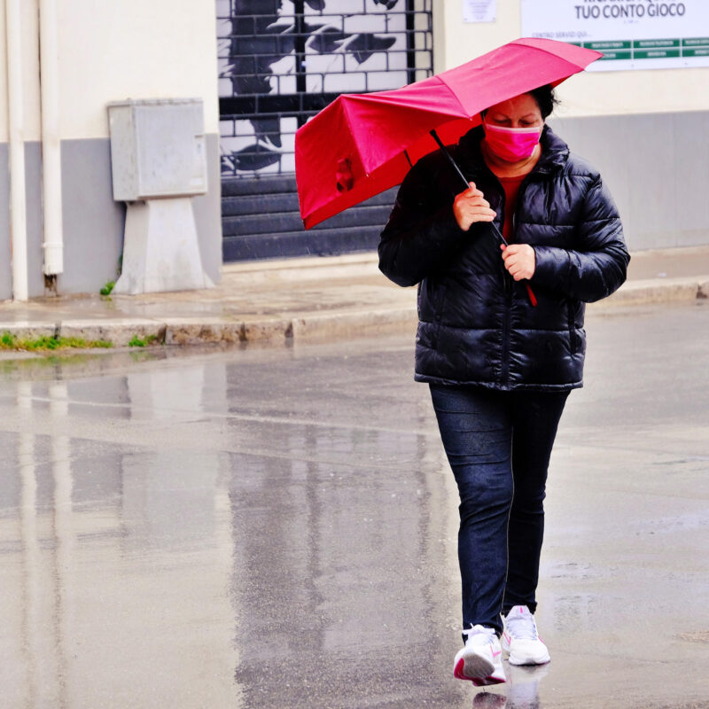 Una donna si ripara dalla pioggia ed il forte vento a Palermo