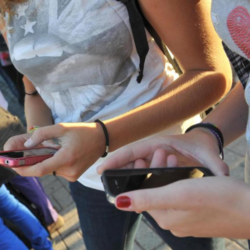 Una foto d'archivio di adolescenti che consultano i loro smartphone