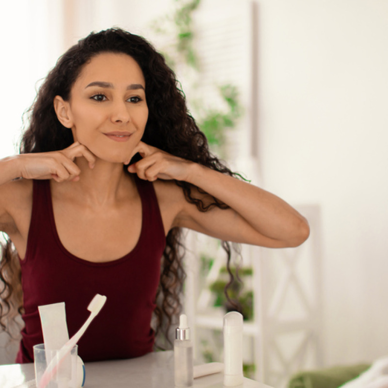 Una donna allo specchio fa auto massaggio al viso per drenare foto iStock.