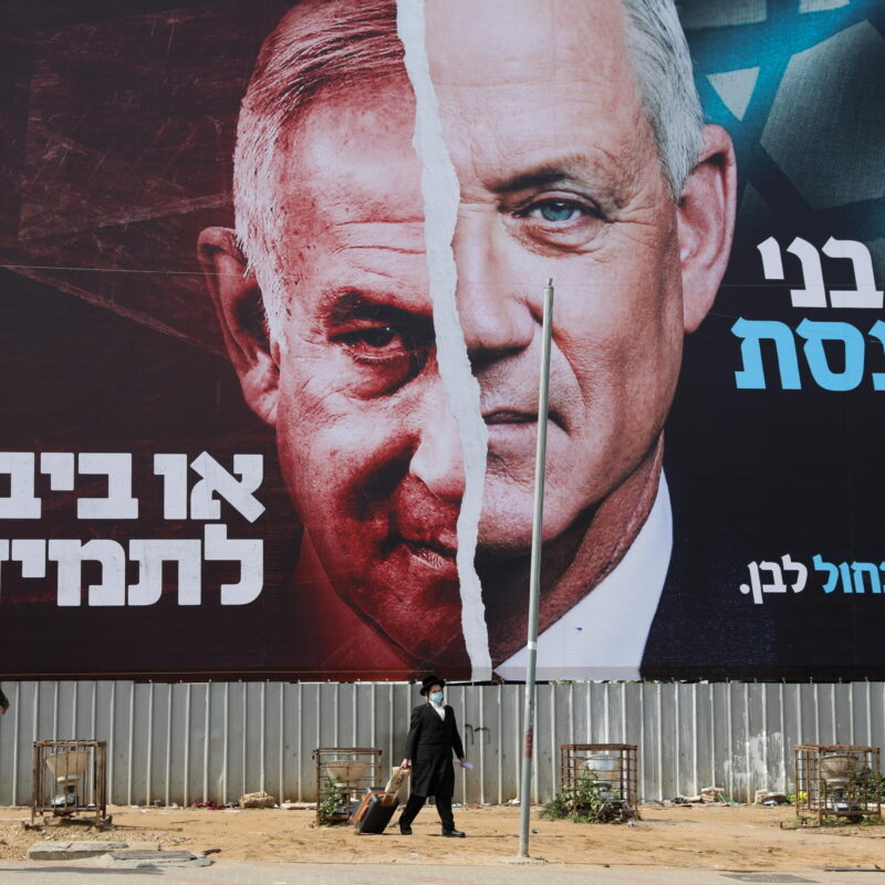epa09073380 People pass by a large election billboard showing Israeli Prime Minister Benjamin Netanyahu and leader of the Blue and white party Beny Gantz in Bnei Brak, near Tel Aviv, Israel, 14 March 2021. Israel is expected to hold legislative elections on 23 March 2021 to elect the members of the 24th Knesset. EPA/ABIR SULTAN