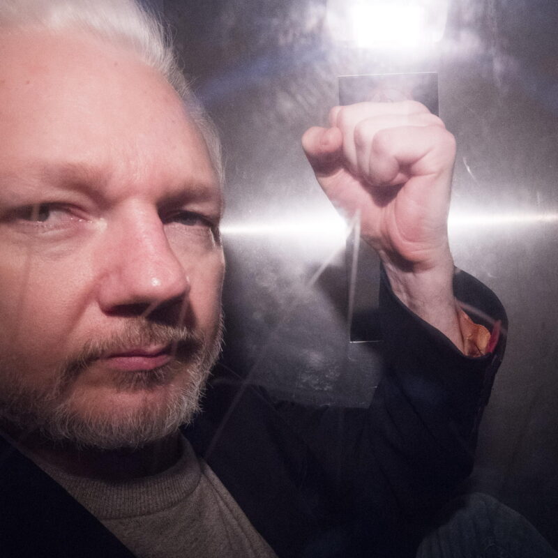 Assange in un furgone carcerario, mentre lascia il carcere di Londra