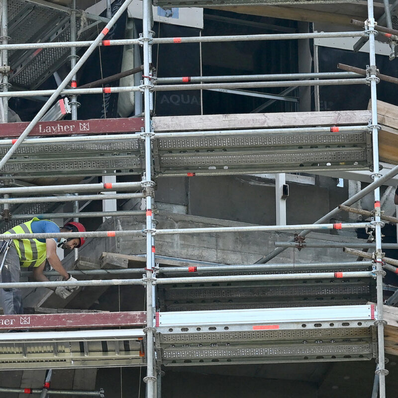 Operai edili al lavoro sulla facciata di un palazzo ricoperto da ponteggi, Milano, 14 giugno 2022. ANSA/DANIEL DAL ZENNARO