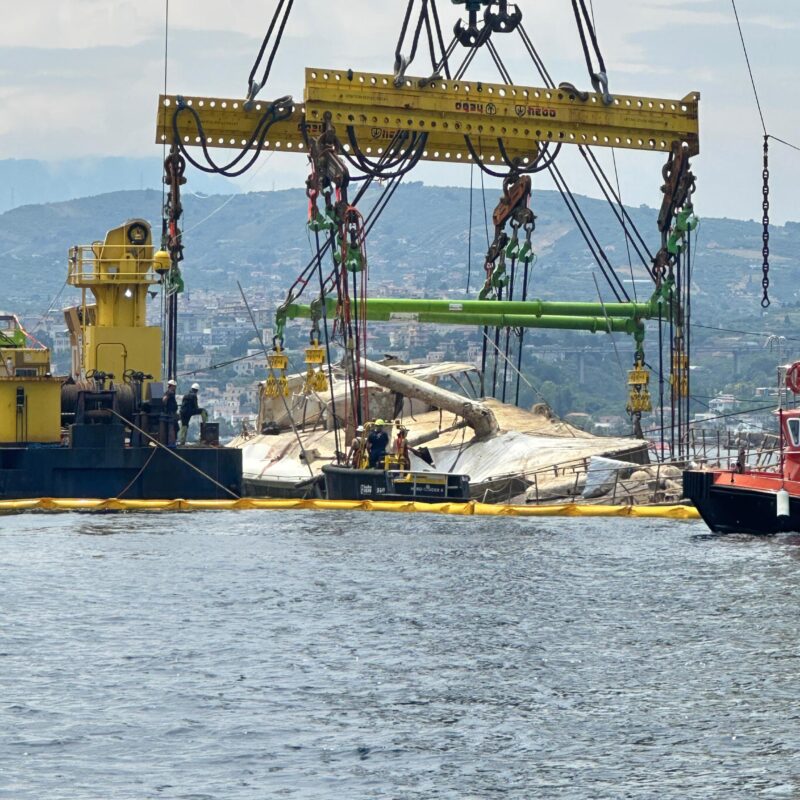 Il Bayesian è stato sollevato a galla dalle gru Hebo per consentire la messa in sicurezza delle imbracature. Lo scafo è riemerso e si trova a pelo d'acqua tra le due gru, Palermo, 20 giugno 2025. ANSA (NPK)